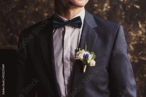 Wedding fashion for men. Closeup of groom's suit, bow tie and boutonniere.