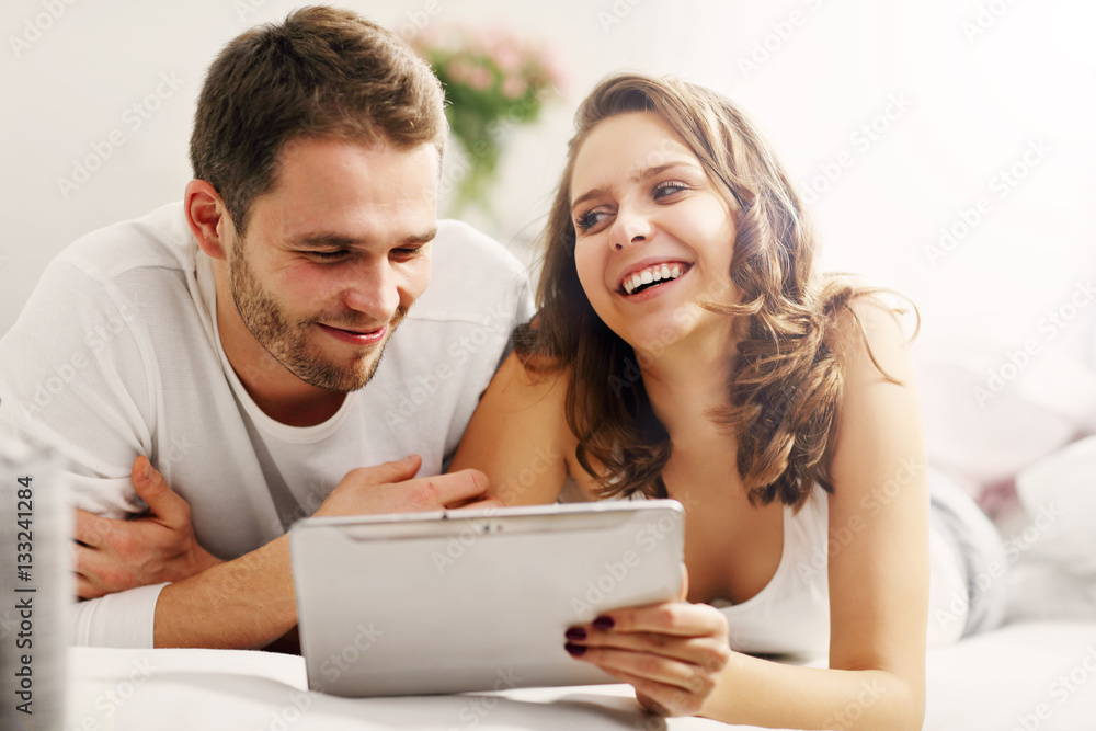Happy couple resting in bedroom with tablet Happy couple resting in bedroom with tablet