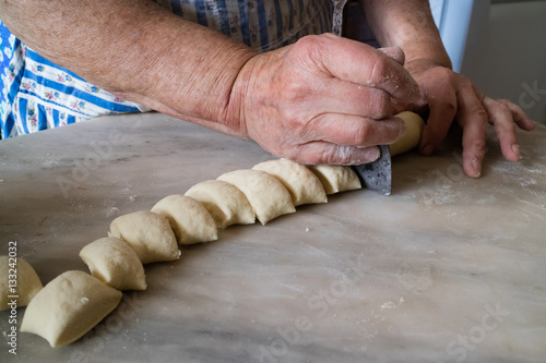 Old woman's hands cutting dough with traditional dough cutter