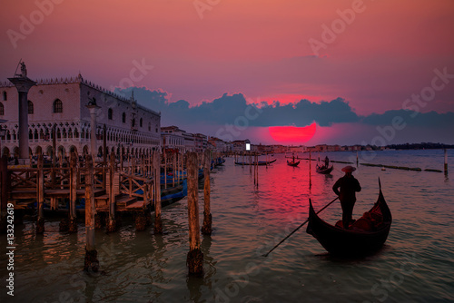 Fototapeta Venetian gondolier punting gondola through green canal waters of Venice Italy