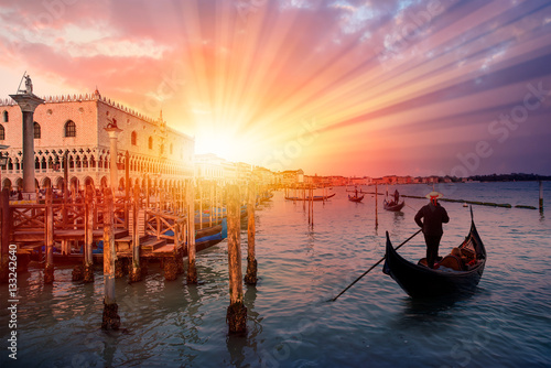 Venetian gondolier punting gondola through green canal waters of Venice Italy © muratart