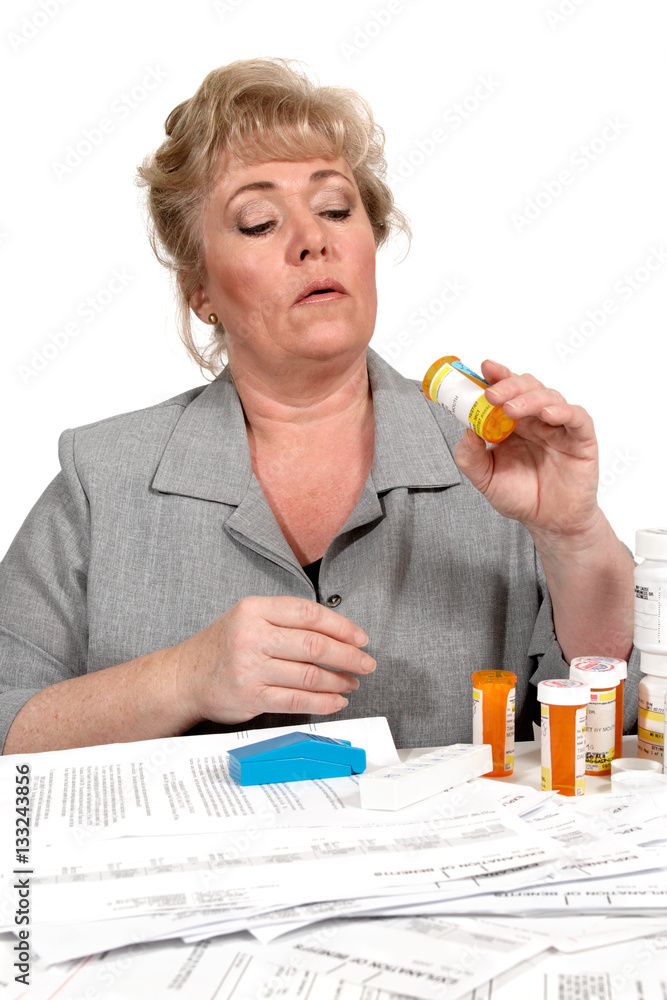Woman reviewing healthcare forms and pills remaining in various bottles Woman reviewing healthcare forms and pills remaining in various bottles