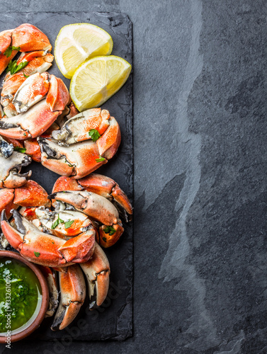 Crabs tentacles with wite wine, lemon, herbs sauce, slate background photo