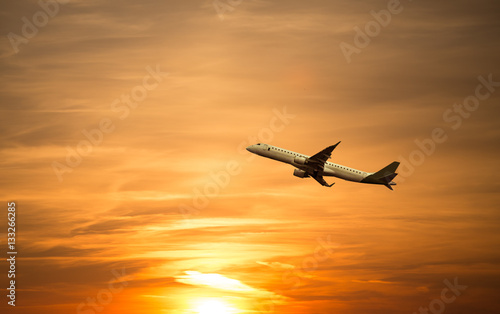A plane flying towards a beautiful sunset