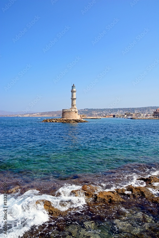 View of the Venetian lighthouse at the harbour entrance with rocks in the foreground, Chania, Crete.