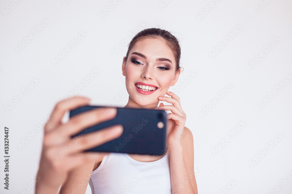 Beautiful brunette girl with makeup make selfie on white background. Beautiful brunette girl with makeup make selfie on white background.