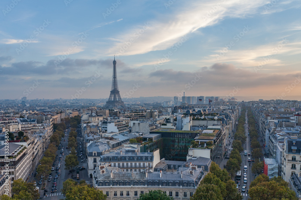 View from Arc de Triomphe in Paris, France towards Eiffel Tower with skyline, blue sky and traffic