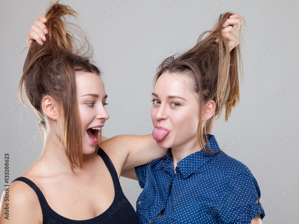 Studio portait of young twin sisters fighting Studio portait of young twin sisters fighting