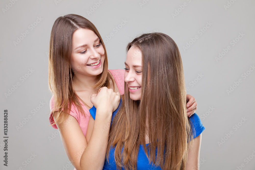 Studio portait of young twin sisters embracing Studio portait of young twin sisters embracing