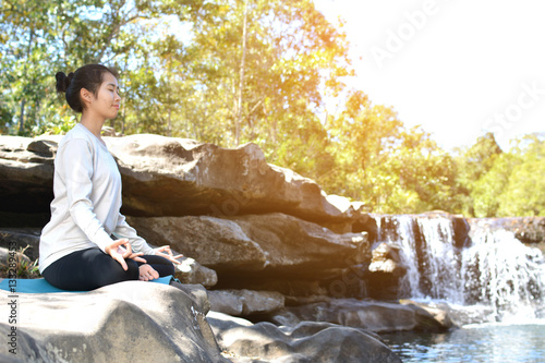 Asian women yoga in nature near waterfall 