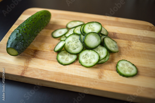 Sliced cucumber lying on a wooden board.