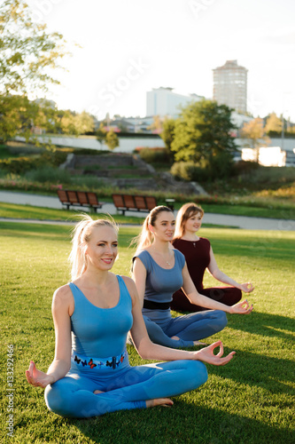 a group of adult women attending yoga outside in the park