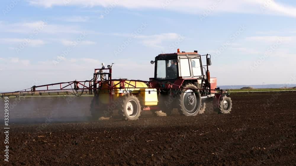 Tractor sprinkles the field with chemicals in sunny spring day. Tractor sprinkles the field with chemicals in sunny spring day.