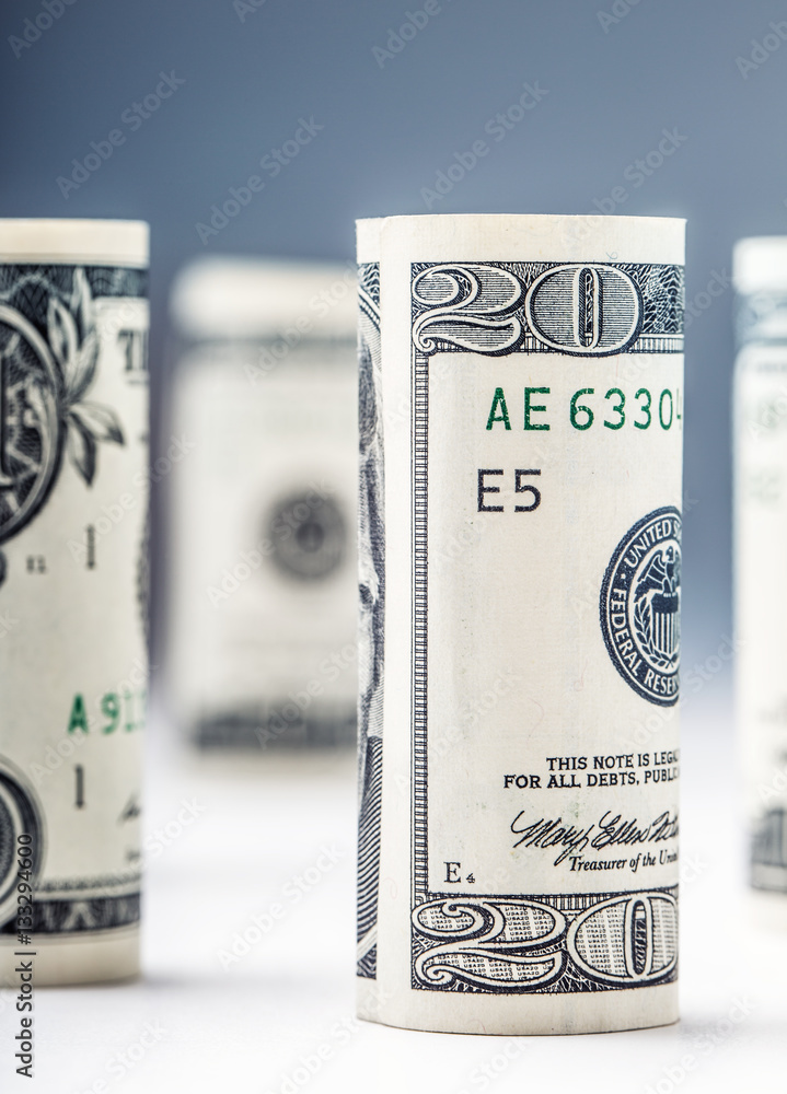 Dollar. Dollar banknotes roll in other positions. American US currency on white board and defocused background. Dollar. Dollar banknotes roll in other positions. American US currency on white board and defocused background.