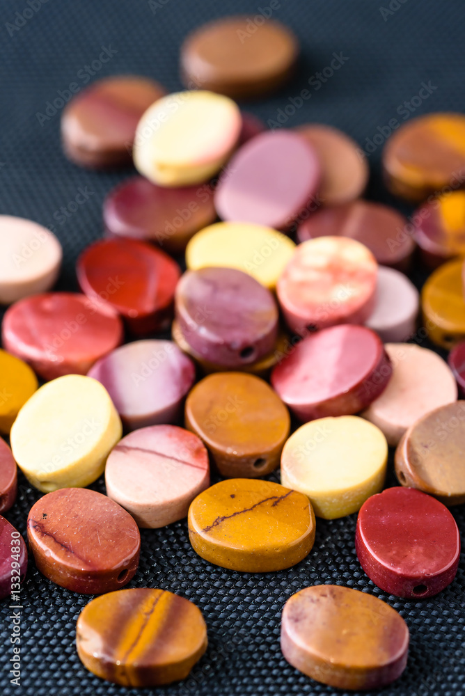 Colorful and polished mookaite jasper beads in oval shape on black weave. Colorful and polished mookaite jasper beads in oval shape on black weave.