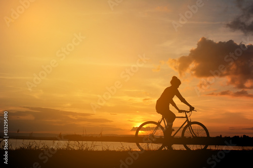 Silhouette of happy women with bicycle in nature at the sky sunset