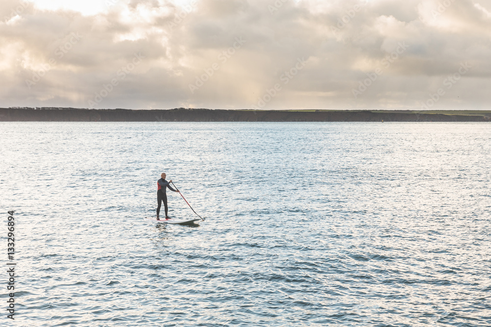 Naklejka premium Man with paddle board over the cliffs