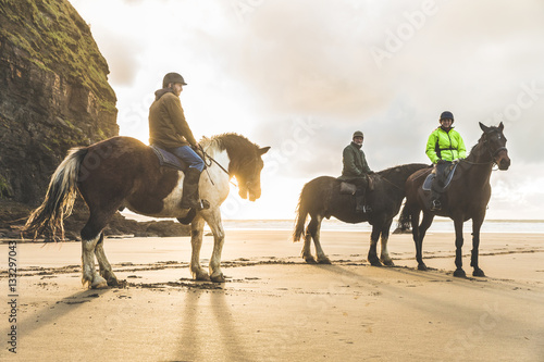 People with horses on the beach on a cloudy day