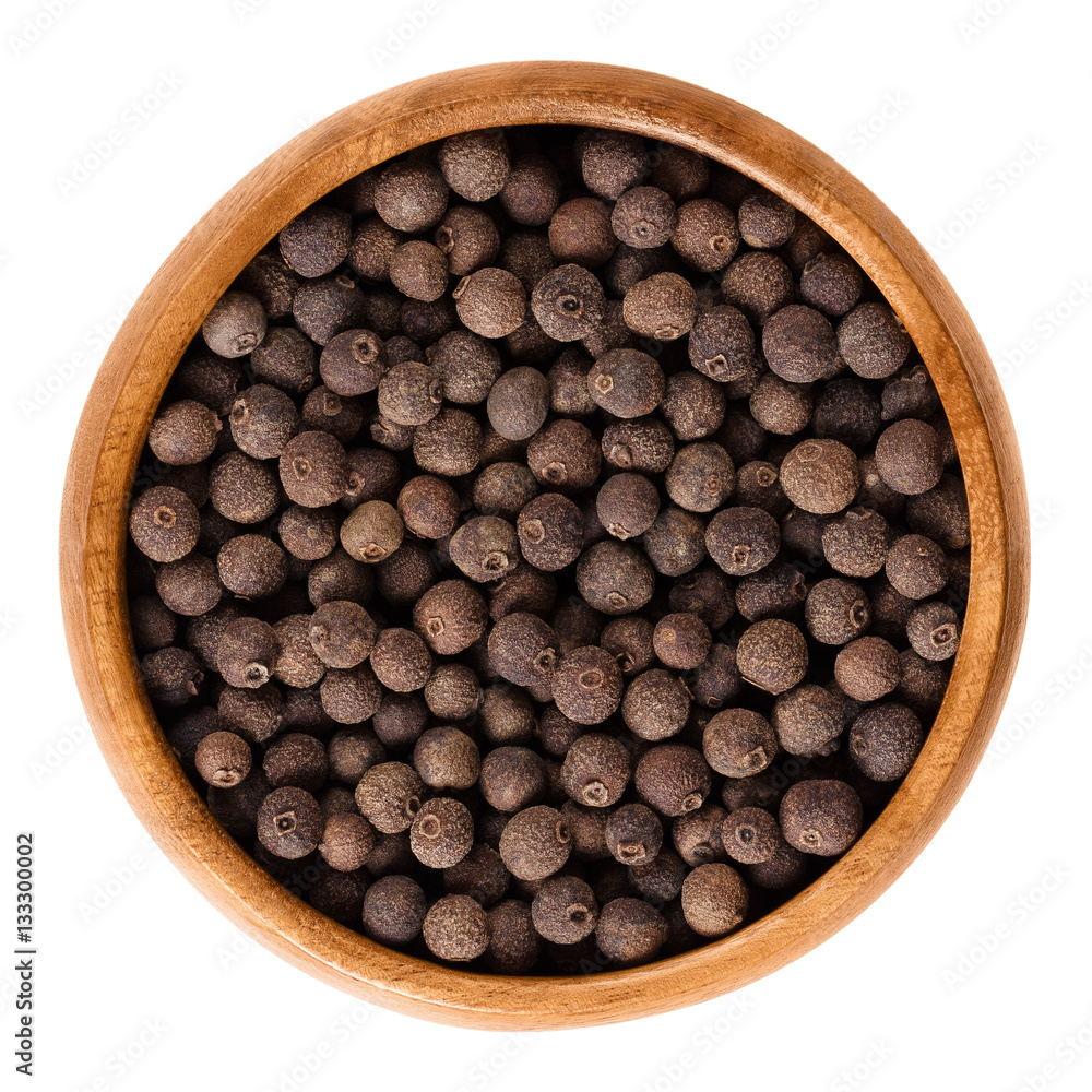 Allspice berries in wooden bowl. Dried unripe fruit, used as spice. Jamaica or myrtle pepper, Turkish yenibahar or newspice. Pimenta dioica, large brown peppercorns. Macro photo on white background. Allspice berries in wooden bowl. Dried unripe fruit, used as spice. Jamaica or myrtle pepper, Turkish yenibahar or newspice. Pimenta dioica, large brown peppercorns. Macro photo on white background.