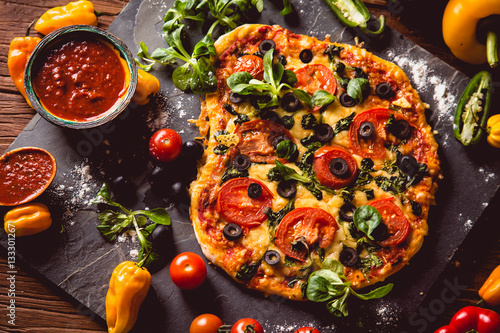Fresh and tasty homemade pizza on wooden table with ingredients