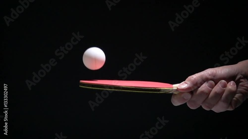 Hand holding table tennis racket and bouncing ping pong ball. Slow motion film clip with sport equipment.