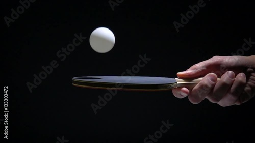 Hand holding table tennis racket and bouncing ping pong ball. Slow motion film clip with sport equipment.