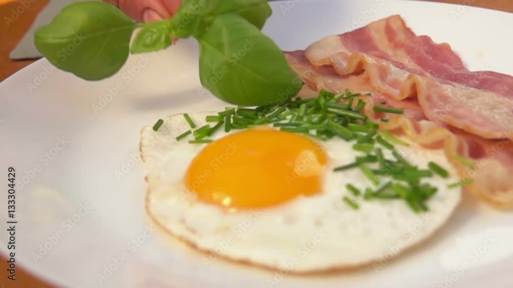 Chef puts a sprig basil on a plate with a traditional breakfast Chef puts a sprig basil on a plate with a traditional breakfast