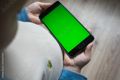 The child is holding a phone in his hand with a green screen for chroma keyer photo