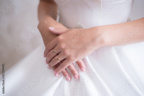 Young bride in wedding dress gently holding her hands with fingers with a ring