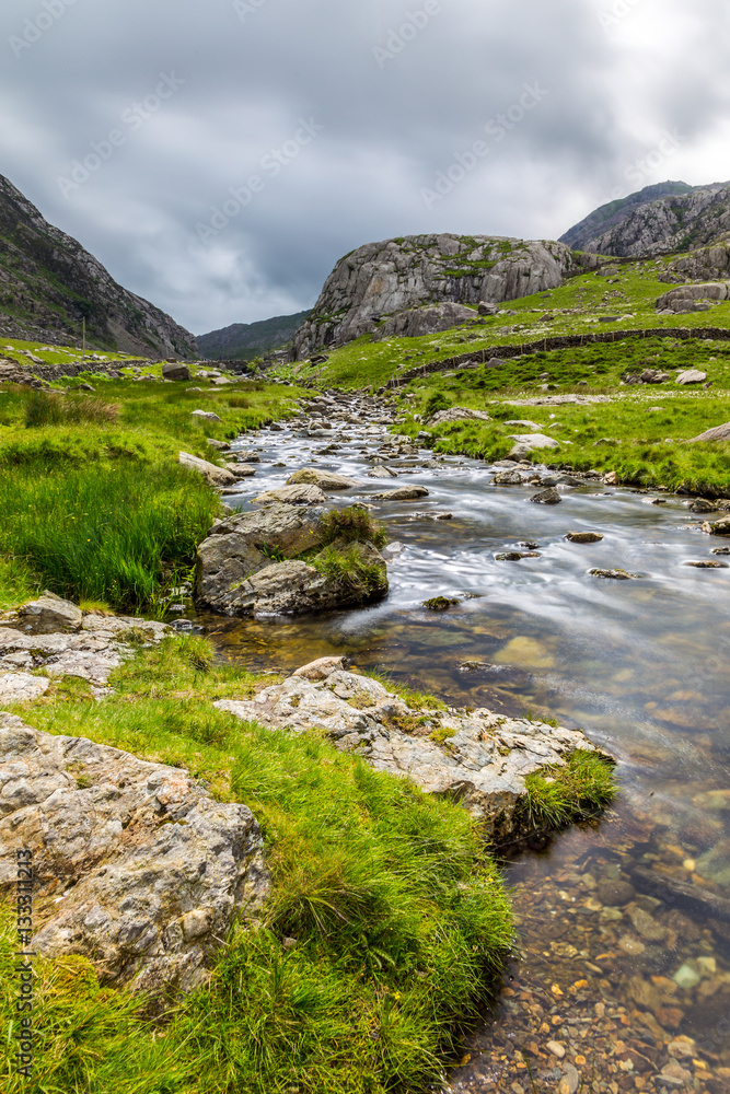 Stream in Llanberis Pass, in Snowdonia from the south-east to Llanberis, over Pen-y-Pass, between the mountain ranges of the Glyderau and the Snowdon massi Stream in Llanberis Pass, in Snowdonia from the south-east to Llanberis, over Pen-y-Pass, between the mountain ranges of the Glyderau and the Snowdon massi