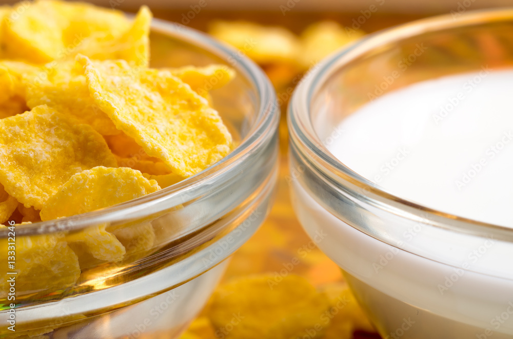 Dry corn flakes and milk in a transparent cups Dry corn flakes and milk in a transparent cups