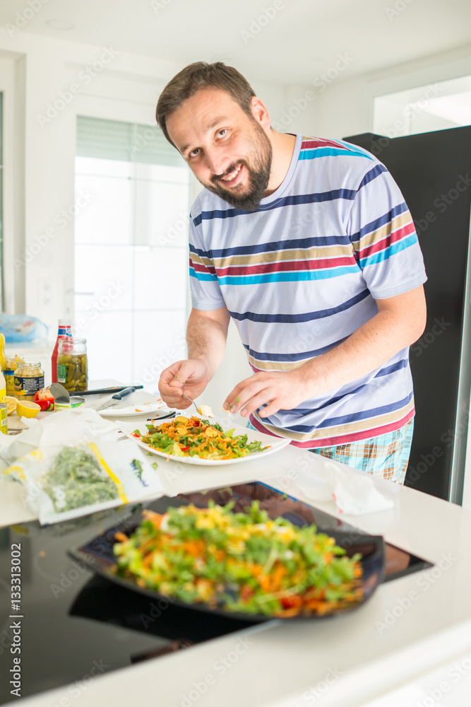 Handsome man cooking at home preparing salad in kitchen Handsome man cooking at home preparing salad in kitchen