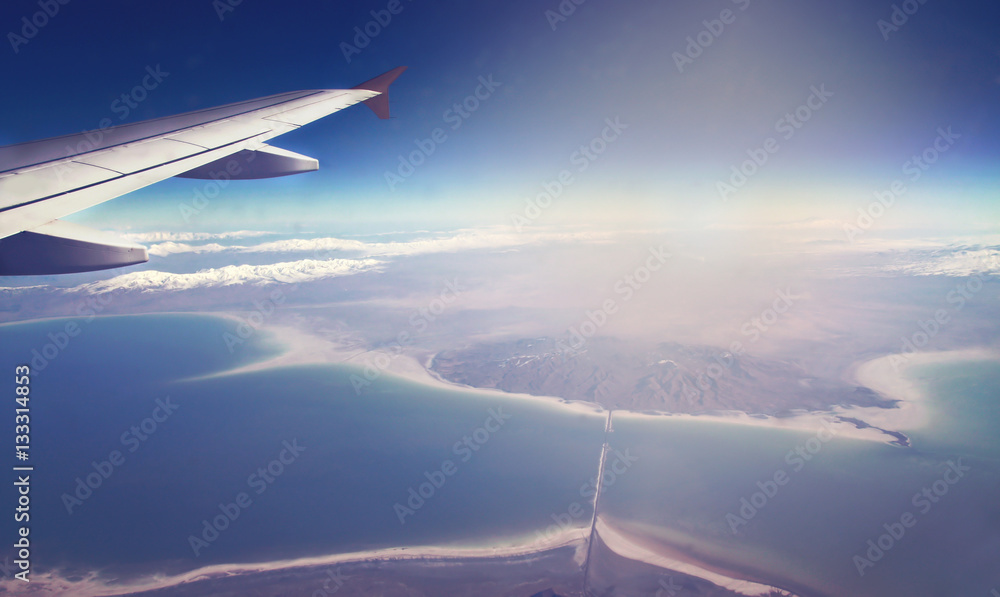 Fototapeta premium Image of plane and wing with sea, mountains, and coastline. Horizont line and sunrise.