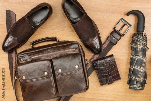 Classic brown suede shoes, briefcase, belt and umbrella on the wooden floor