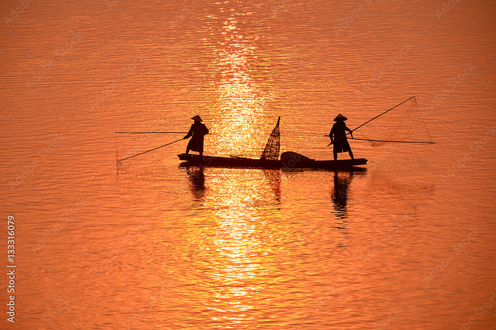 Naklejka premium The silluate fisherman boat in river on during sunrise,Thailand