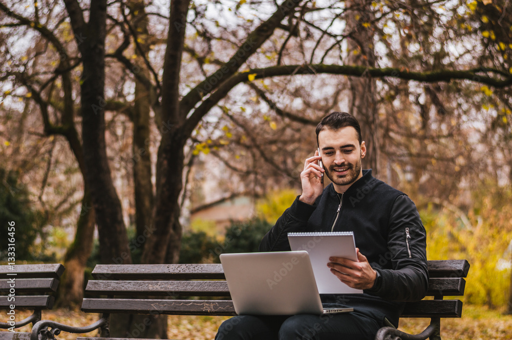 Handsome man working on his laptop in the park Handsome man working on his laptop in the park