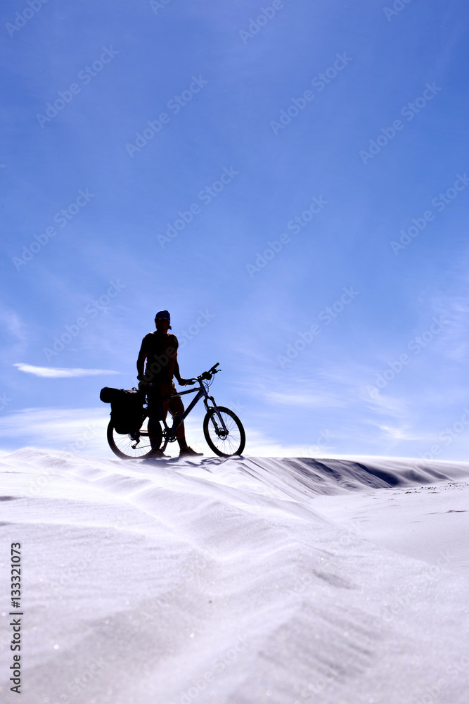 Fototapeta premium Traveling man on a bicycle in the desert.