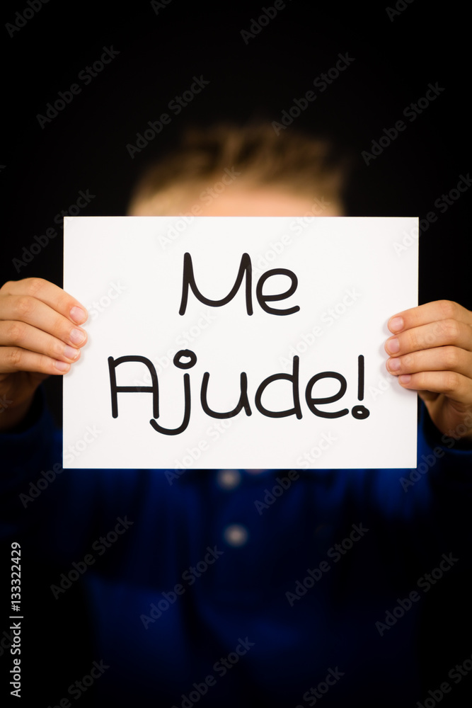 Child holding sign with Portuguese words Me Ajude - Help Me Child holding sign with Portuguese words Me Ajude - Help Me