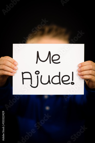 Child holding sign with Portuguese words Me Ajude - Help Me
