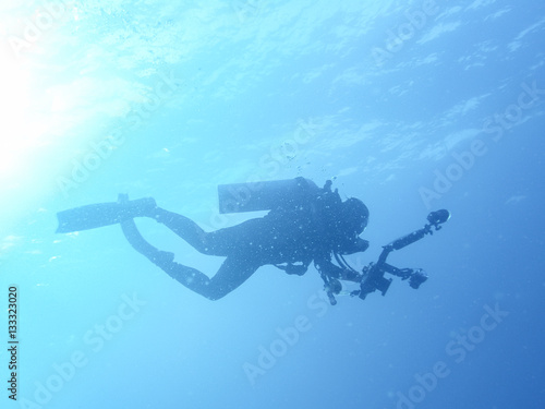 silhouette of underwater photographer scuba diving with professional camera