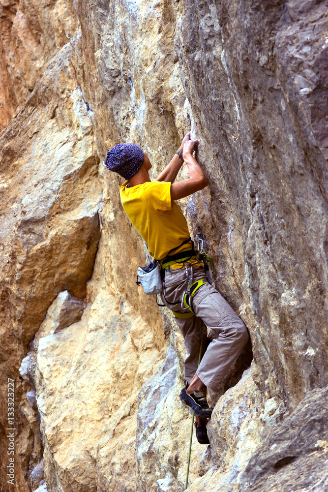 Young male climber hanging on a cliff with a rope. 