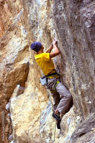 Young male climber hanging on a cliff with a rope. 
