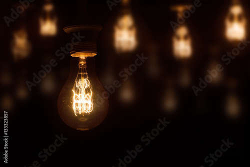 lighted vintage incandescent bulb on dark orange blurred background