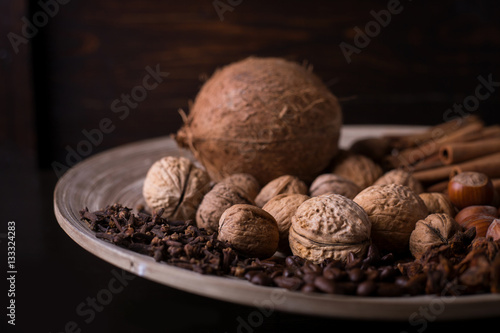 rose, cinnamon sticks, star anise, cloves, nuts, coconut, coffee beans on a wooden background