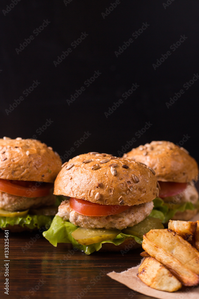 Three burgers on a dark wooden table