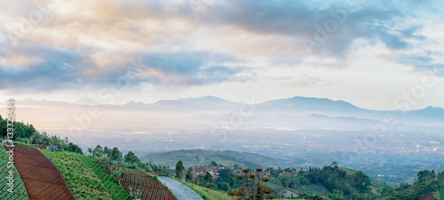 Panorama of plantation area on top of the hill and scenery of city when illuminated by sunlightin faraway, captured  from Moko Hills when weather is sunny, Bandung, Indonesia