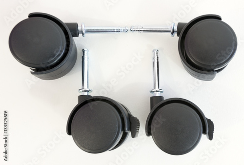Set of four plastic unattached furniture wheels. White background. Horizontal.