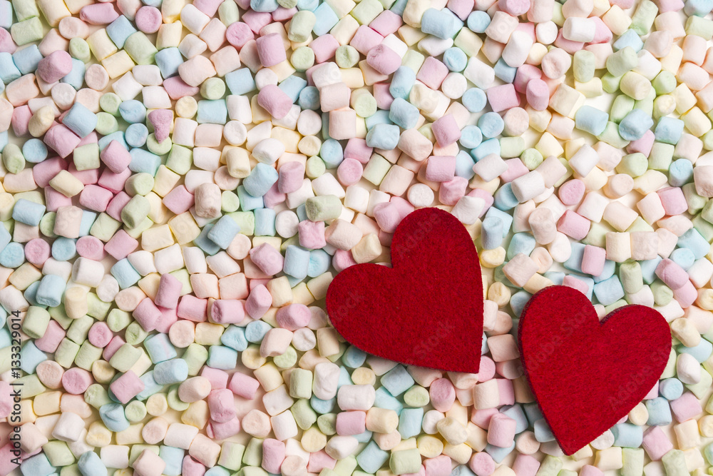 Two red hearts on colorful mini marshmallows background Two red hearts on colorful mini marshmallows background