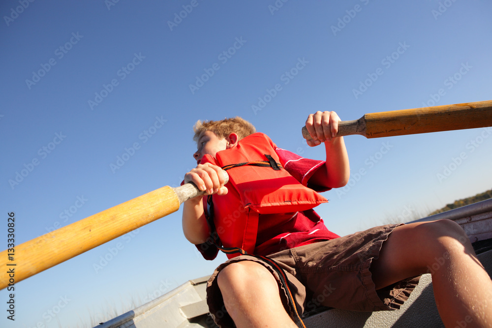 Fotografie Boy rowing a boat on a lake