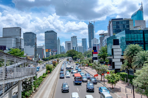 Beautiful skyline of Jakarta, Indonesia. Showing modern skyscraper buildings and beautiful blue sky and white cloud at afternoon and big road with moderate traffic. Captured in Jend. Sudirman Street